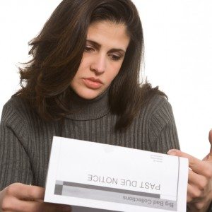 Young woman looks sad with past due notices in front of her